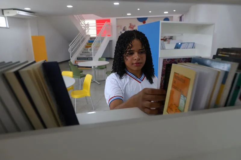 A student browsing through the bookshelves in a modern school library, reflecting a focused learning environment.
