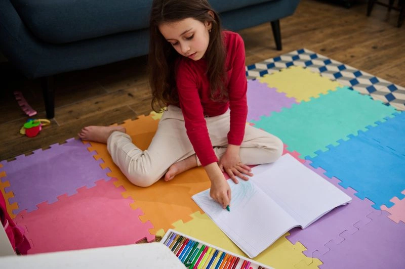 A young girl deeply focused on her drawing, showcasing the creative abilities of gifted and talented students, using color and imagination to express herself.