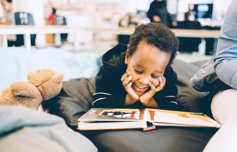 Child developing early literacy skills by reading a picture book at home