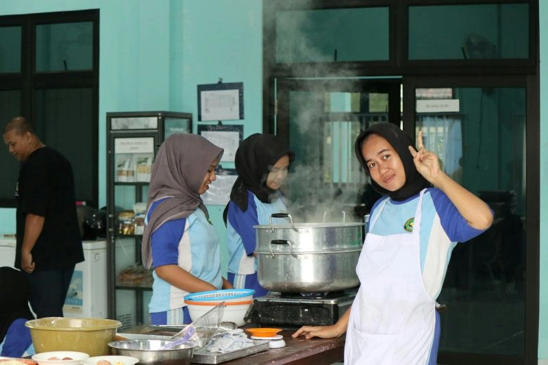 Students participating in student teamwork activities while preparing food together in a school kitchen