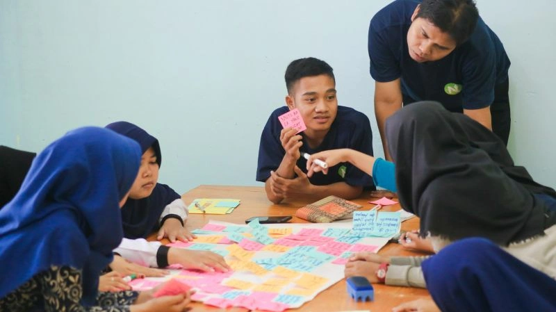 Students practicing student teamwork during a classroom brainstorming session with notes and group discussion